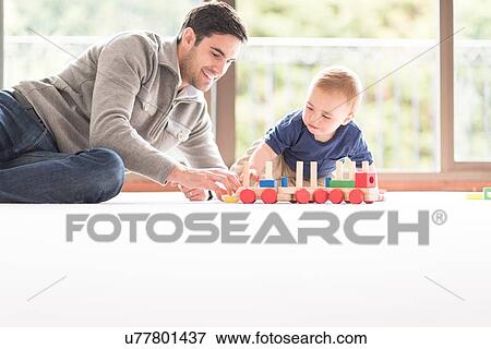 "Father and young son playing together, indoors" View Large Photo Image Stock Photo - "Father and young son playing together, indoors". Fotosearch