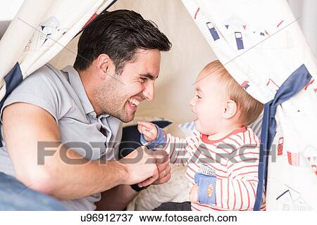 "Father and young son sitting in play tent indoors, laughing together" View Large Photo Image Stock Photo - "Father and young son sitting in play tent indoors, laughing together". Fotosearch