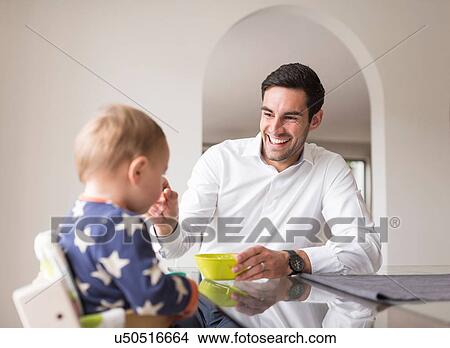 "Father feeding young son, indoors" View Large Photo Image Picture - "Father feeding young son, indoors". Fotosearch