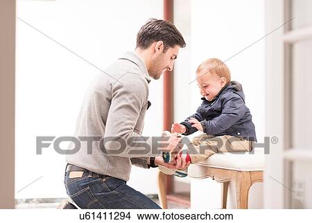 Father helping young son put shoes on View Large Photo Image Picture - Father helping young son put shoes on. Fotosearch
