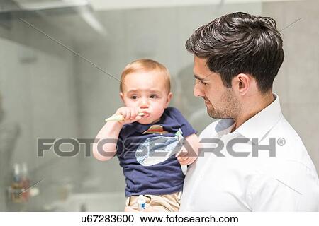 Father holding young son while son brushes teeth View Large Photo Image Stock Image - Father holding young son while son brushes teeth. Fotosearch