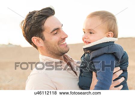Stock Photo - "Father hugging young son, outdoors". Fotosearch