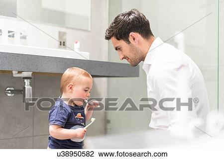 Father watching young brush teeth View Large Photo Image Stock Image - Father watching young brush teeth. Fotosearch
