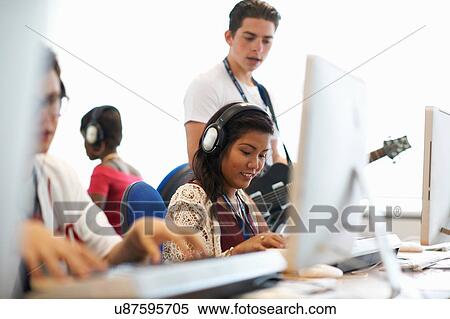 Female college student wearing headphones playing keyboards looking down smiling View Large Photo Image Stock Photography - Female college student wearing headphones playing keyboards looking down smiling. Fotosearch