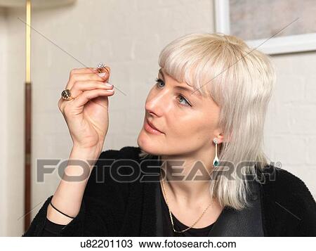 Stock Image - Female jeweler examining ring in jewellery shop. Fotosearch