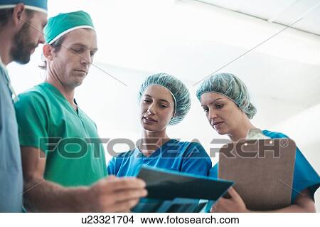 Four male and female orthopedic surgeons reviewing x-ray image View Large Photo Image Picture - Four male and female orthopedic surgeons reviewing x-ray image. Fotosearch