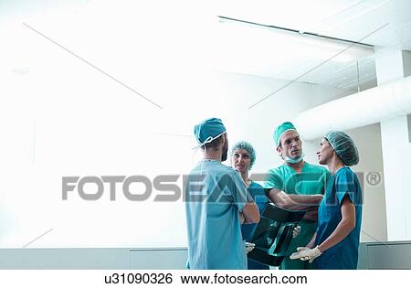 Stock Photograph - Four male and female orthopedic surgeons discussing x-ray image in hospital. Fotosearch