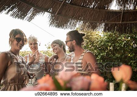 "Friends waist up standing under straw parasol holding drinks, smiling" View Large Photo Image Stock Photography - "Friends waist up standing under straw parasol holding drinks, smiling". Fotosearch