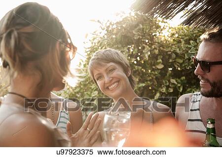 "Friends waist up standing under straw parasol holding drinks, smiling" View Large Photo Image Stock Photography - "Friends waist up standing under straw parasol holding drinks, smiling". Fotosearch