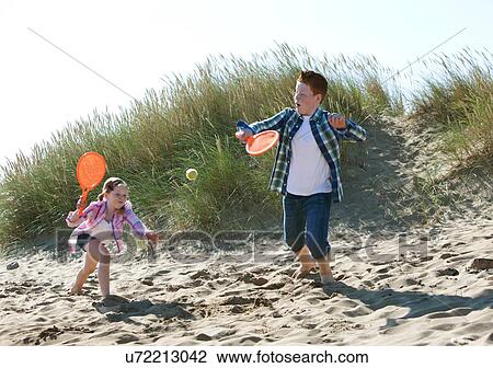 Girl and boy playing with orange sports bat and tennis ball on dunes View Large Photo Image Stock Image - Girl and boy playing with orange sports bat and tennis ball on dunes. Fotosearch