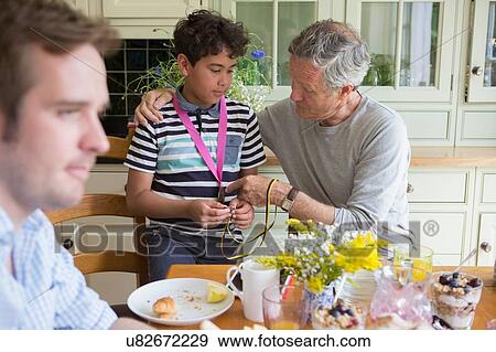 Grandfather and grandson looking at medals around grandson's neck View Large Photo Image Stock Photo - Grandfather and grandson looking at medals around grandson's neck. Fotosearch