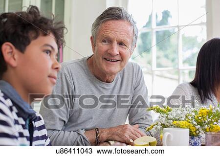 Grandfather and grandson sitting at dinner table together View Large Photo Image Stock Image - Grandfather and grandson sitting at dinner table together. Fotosearch