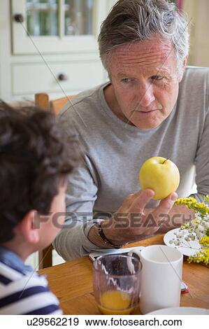 Grandfather offering apple to grandson View Large Photo Image Stock Photo - Grandfather offering apple to grandson. Fotosearch