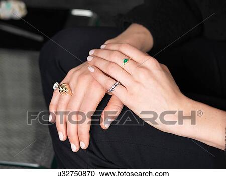 Stock Image - Hands of female jeweler wearing variety of rings in jewellery shop. Fotosearch