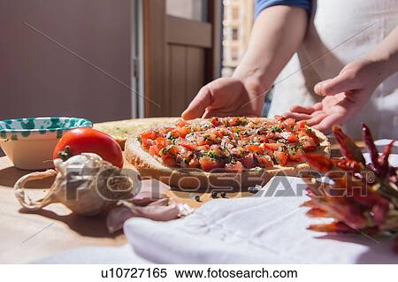 Stock Photography - Hands of woman lifting bread pizza from kitchen counter. Fotosearch