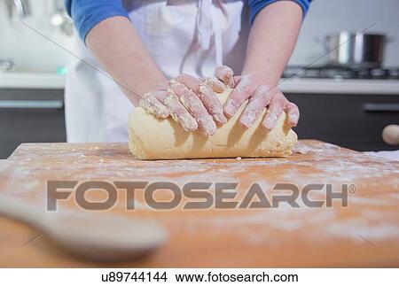 Picture - Hands of woman rolling dough at kitchen counter. Fotosearch