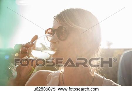Head and shoulders of young woman wearing sunglasses drinking from wine glass looking away View Large Photo Image Stock Photography - Head and shoulders of young woman wearing sunglasses drinking from wine glass looking away. Fotosearch