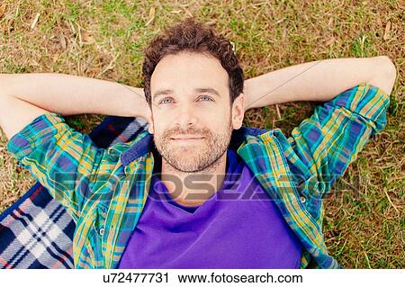High angle view of mid adult man lying on blanket hands behind head looking away smiling View Large Photo Image Stock Image - High angle view of mid adult man lying on blanket hands behind head looking away smiling. Fotosearch