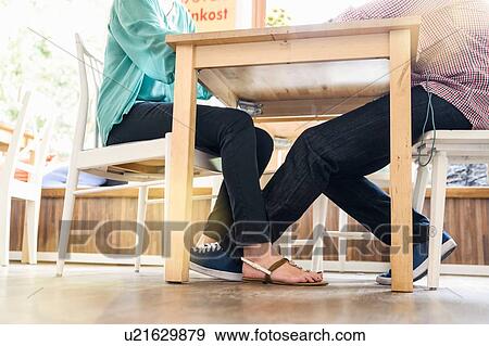 Low angle view of couple from neck down sitting face to face at cafe table View Large Photo Image Stock Photo - Low angle view of couple from neck down sitting face to face at cafe table. Fotosearch