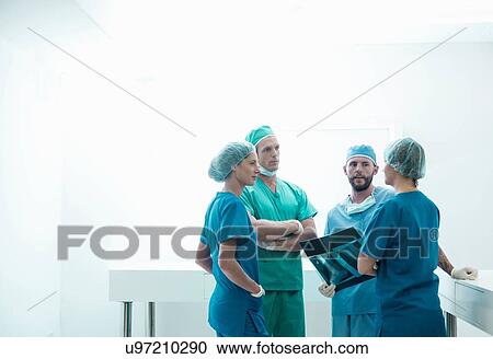 Stock Image - Male and female orthopedic surgeons discussing x-ray image in hospital. Fotosearch