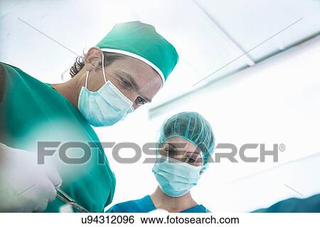Male and female surgeons operating in hospital operating theatre View Large Photo Image Stock Photograph - Male and female surgeons operating in hospital operating theatre. Fotosearch