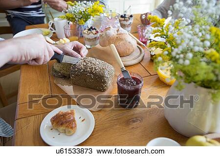 Stock Image - "Man slicing granary bread in preparation for breakfast, focus con hands". Fotosearch