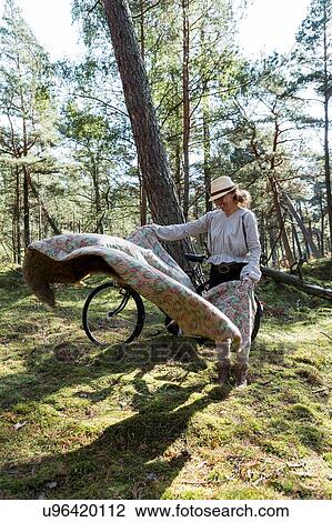 Mature female cyclist laying down blanket on forest floor View Large Photo Image Stock Image - Mature female cyclist laying down blanket on forest floor. Fotosearch
