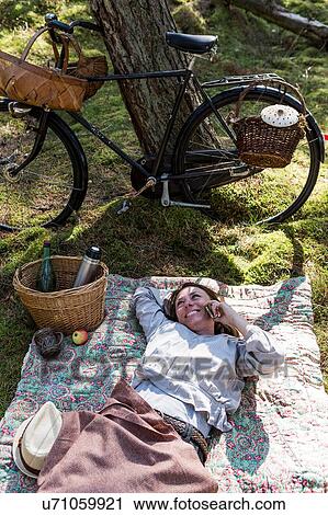 Mature female forager resting on blanket in forest talking on smartphone View Large Photo Image Stock Image - Mature female forager resting on blanket in forest talking on smartphone. Fotosearch