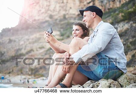 "Mature man and teenage daughter reading smartphone texts on rocky beach, Javea, Spain" View Large Photo Image Stock Photo - "Mature man and teenage daughter reading smartphone texts on rocky beach, Javea, Spain". Fotosearch