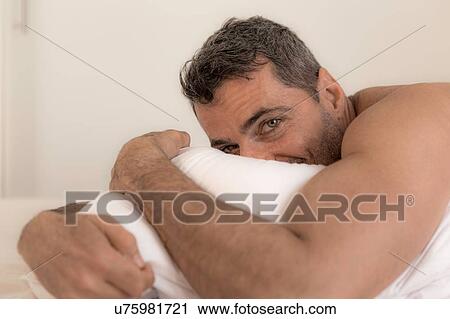 "Mature man lying on front hugging pillow, looking at camera, face partially obscured" View Large Photo Image Stock Image - "Mature man lying on front hugging pillow, looking at camera, face partially obscured". Fotosearch