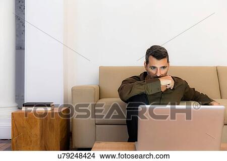 "Mature man sitting on floor looking at laptop, arm over mouth" View Large Photo Image Picture - "Mature man sitting on floor looking at laptop, arm over mouth". Fotosearch