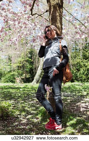 Mature woman chatting on smartphone whilst leaning against park tree View Large Photo Image Stock Photo - Mature woman chatting on smartphone whilst leaning against park tree. Fotosearch