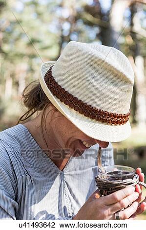 Stock Image - Mature woman laughing whilst drinking tea in forest. Fotosearch
