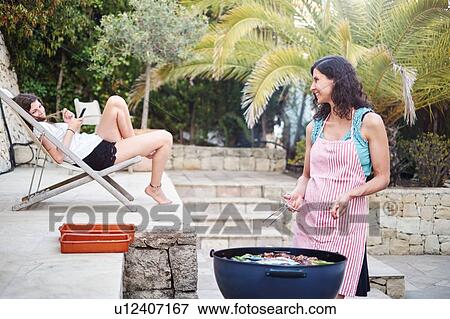 Mature woman preparing barbecued food for teenage daughter on patio View Large Photo Image Stock Photo - Mature woman preparing barbecued food for teenage daughter on patio. Fotosearch