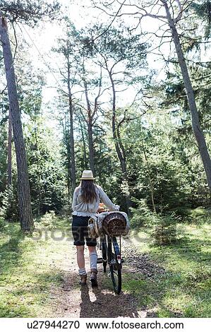 Mature woman pushing bicycle with foraging baskets on forest path View Large Photo Image Stock Image - Mature woman pushing bicycle with foraging baskets on forest path. Fotosearch