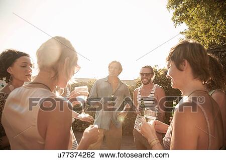 Medium group of friends standing in a circle holding drinks talking and smiling View Large Photo Image Stock Image - Medium group of friends standing in a circle holding drinks talking and smiling. Fotosearch