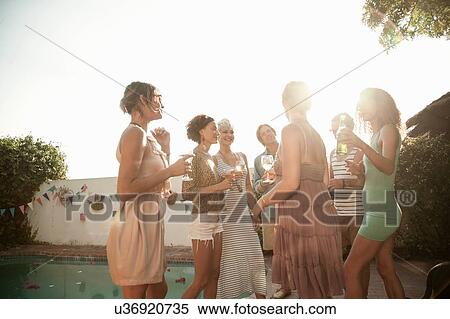 Medium group of friends standing in a circle next to swimming pool holding drinks smiling View Large Photo Image Stock Photography - Medium group of friends standing in a circle next to swimming pool holding drinks smiling. Fotosearch
