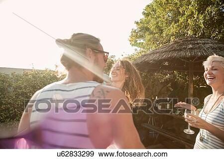 Stock Photo - Men and young women friends drinking at poolside party. Fotosearch