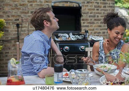 Stock Photograph - Mid adult couple eating meal outdoors. Fotosearch