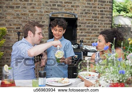 "Mid adult couple with son, eating meal outdoors" View Large Photo Image Picture - "Mid adult couple with son, eating meal outdoors". Fotosearch