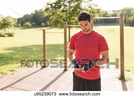 Stock Image - "Mid adult man in park, preparing for workout". Fotosearch