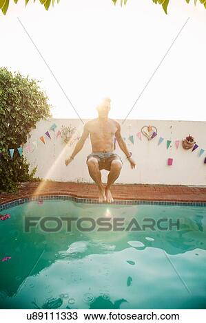 Mid adult man jumping into swimming pool at poolside party View Large Photo Image Stock Image - Mid adult man jumping into swimming pool at poolside party. Fotosearch