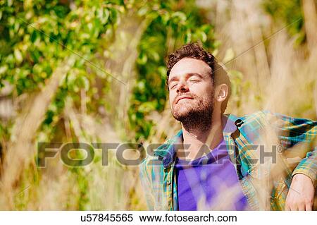 Mid adult man sitting in tall grass eyes closed basking in sunlight View Large Photo Image Stock Photography - Mid adult man sitting in tall grass eyes closed basking in sunlight. Fotosearch