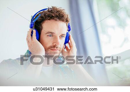 "Mid adult man wearing headphones, hands to ears, looking away" View Large Photo Image Stock Image - "Mid adult man wearing headphones, hands to ears, looking away". Fotosearch
