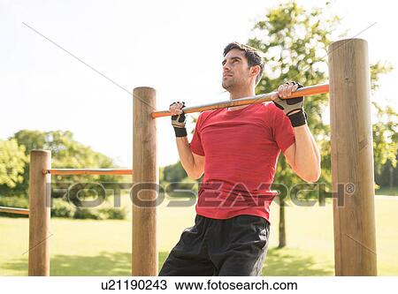 Stock Image - Mid adult man working out in park. Fotosearch