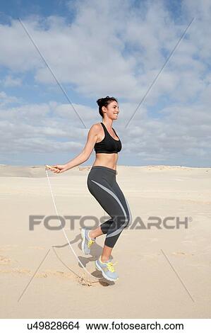 Mid adult woman exercising with skipping rope on beach View Large Photo Image Picture - Mid adult woman exercising with skipping rope on beach. Fotosearch