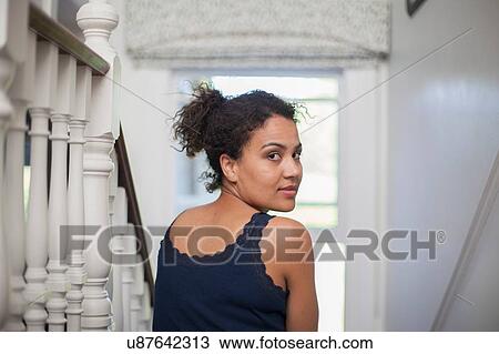 "Mid adult woman sitting on stairs, looking over shoulder" View Large Photo Image Stock Image - "Mid adult woman sitting on stairs, looking over shoulder". Fotosearch