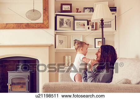 Mother and baby boy playing in living room View Large Photo Image Stock Image - Mother and baby boy playing in living room. Fotosearch