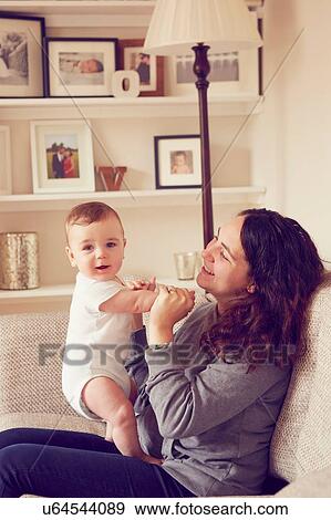Stock Photo - Mother and baby boy playing in living room. Fotosearch