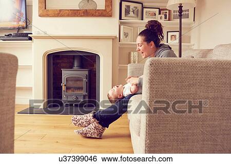 Stock Photograph - Mother and baby boy playing in living room. Fotosearch